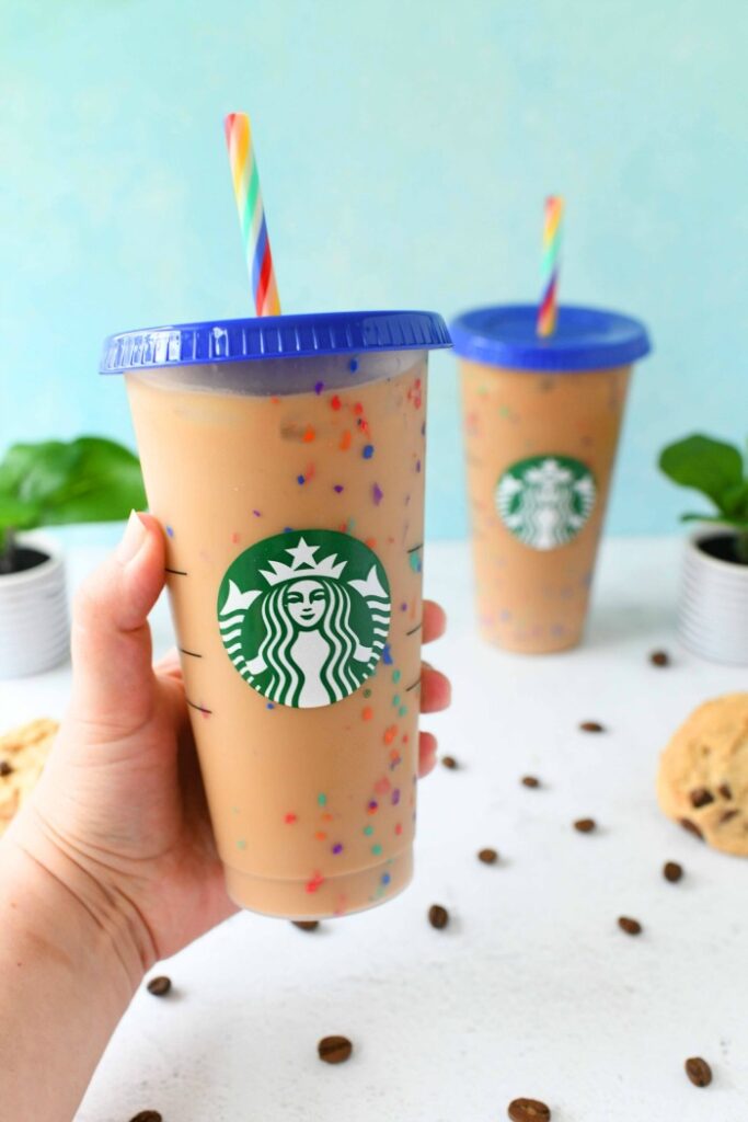 Starbucks Rainbow Cups with blue lid with blue background in a hand.