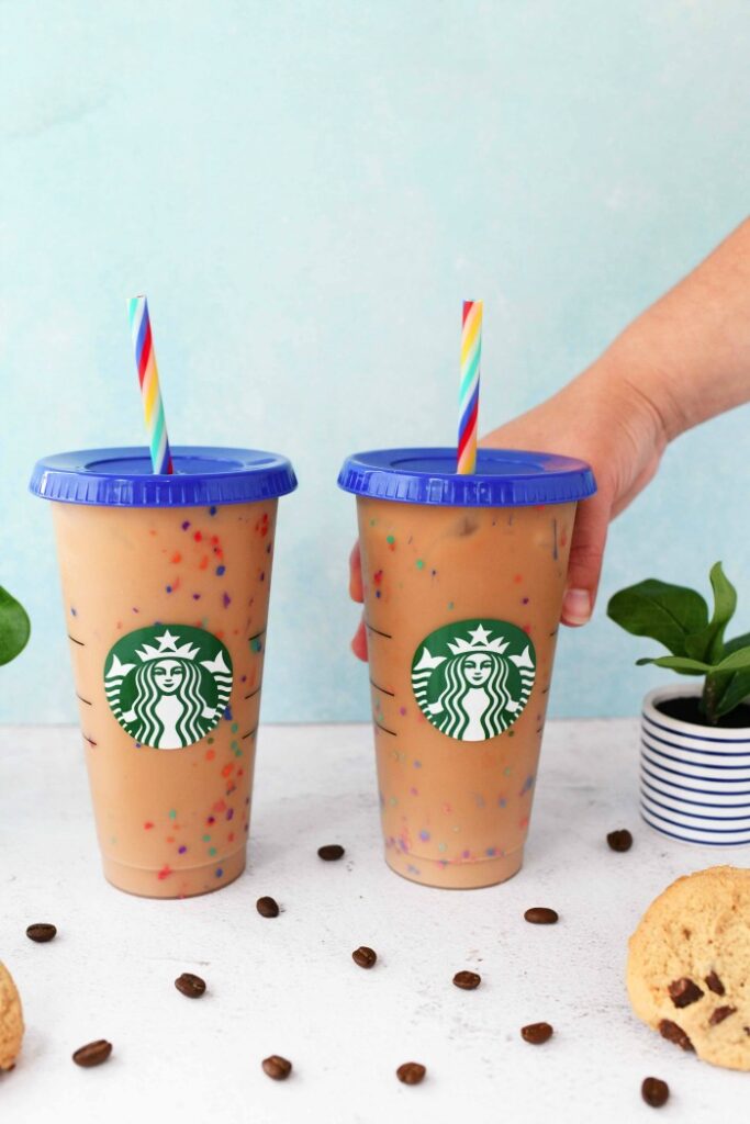 Starbucks Rainbow Cups in hand near a blue background