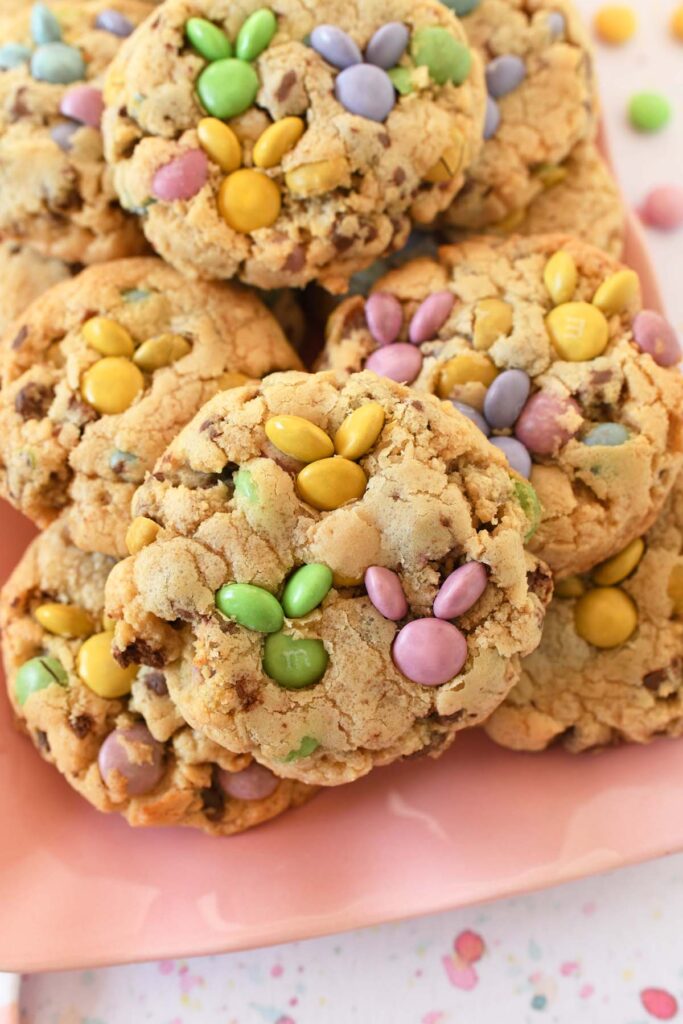An up-close shot of jumbo M&M Bunny cookies on a pink platter on a speckled surface.