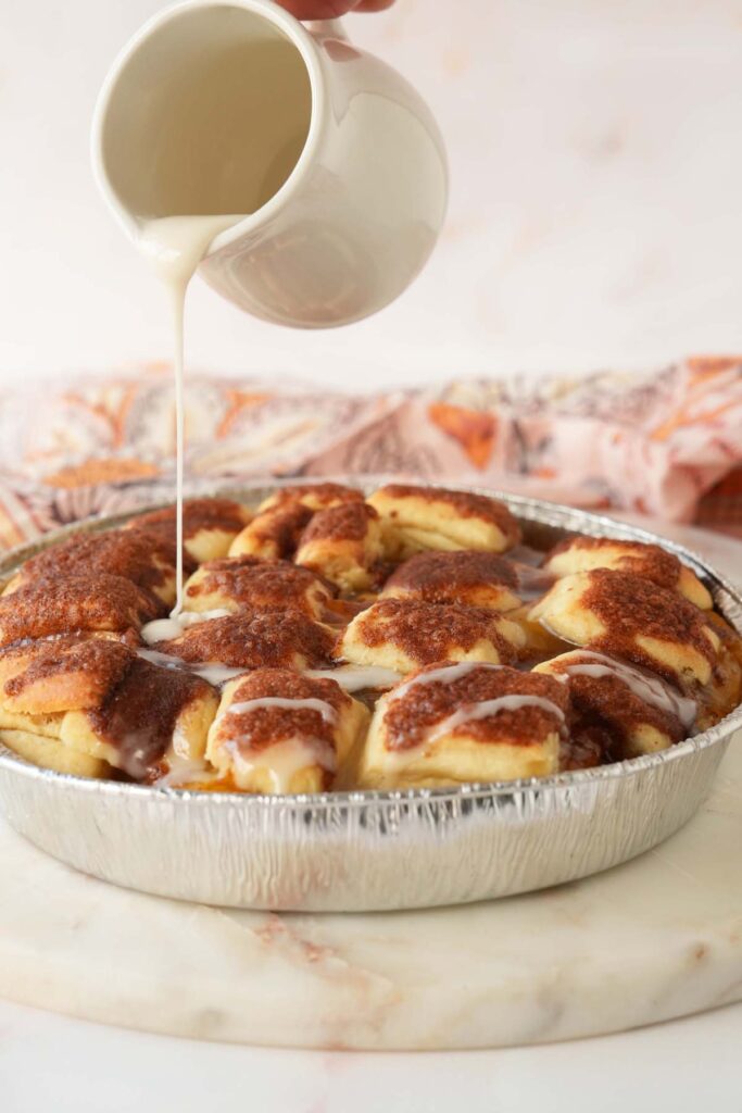 Drizzling icing on peach dumplings.