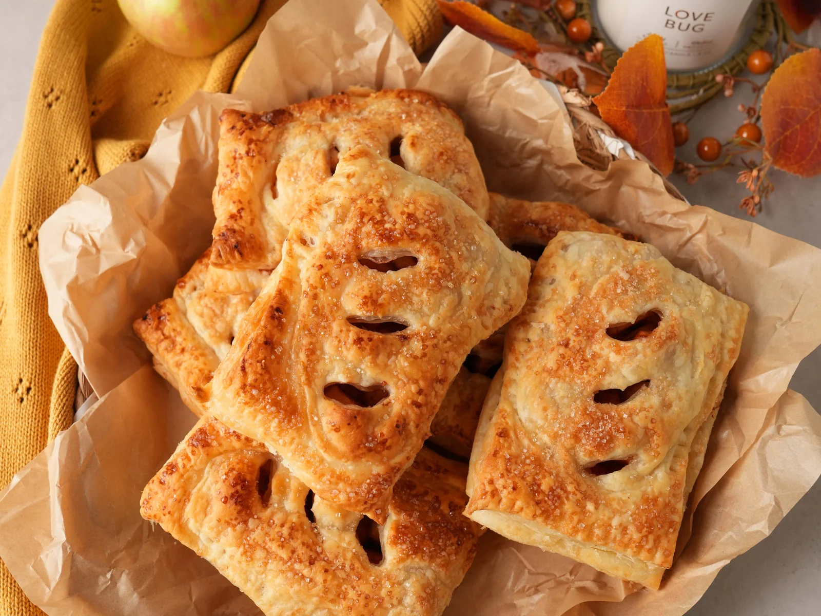 Golden puff pastry apple hand pies styled with fresh apples and warm autumn accents.