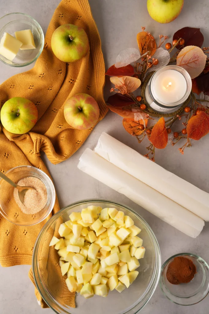 Puff pastry, diced apples, butter, cinnamon, and autumn styling for apple hand pies.