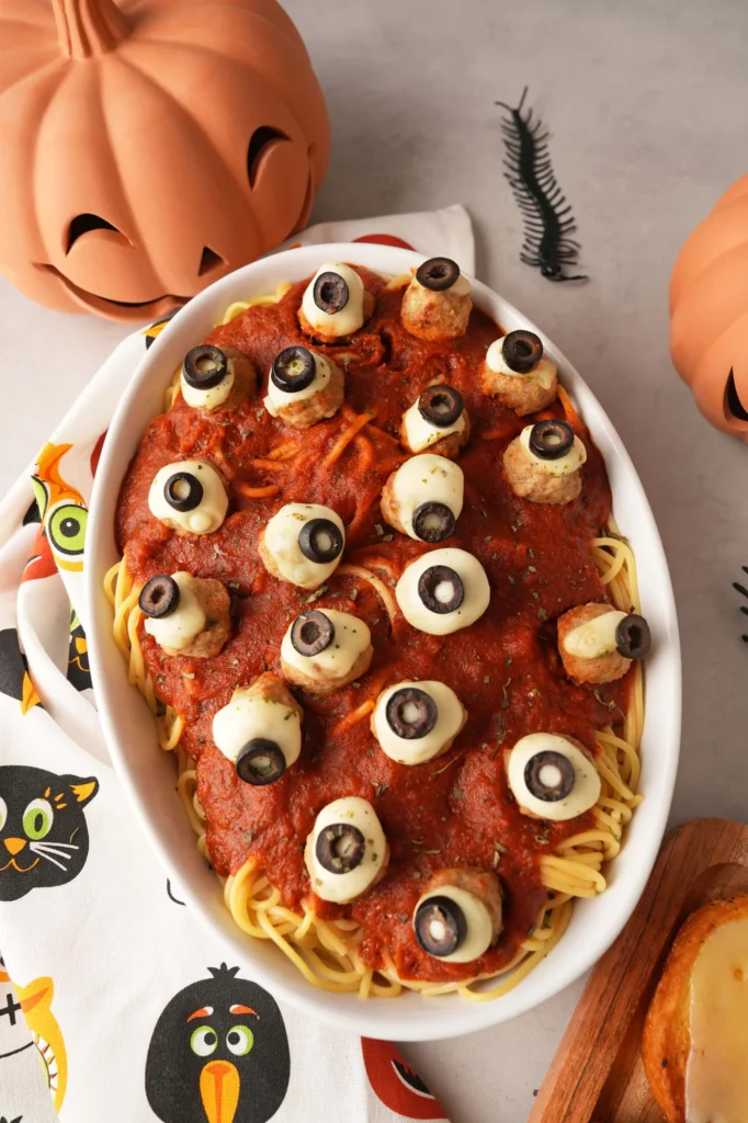 Close-up of Halloween eyeball meatballs over spaghetti and tomato sauce.