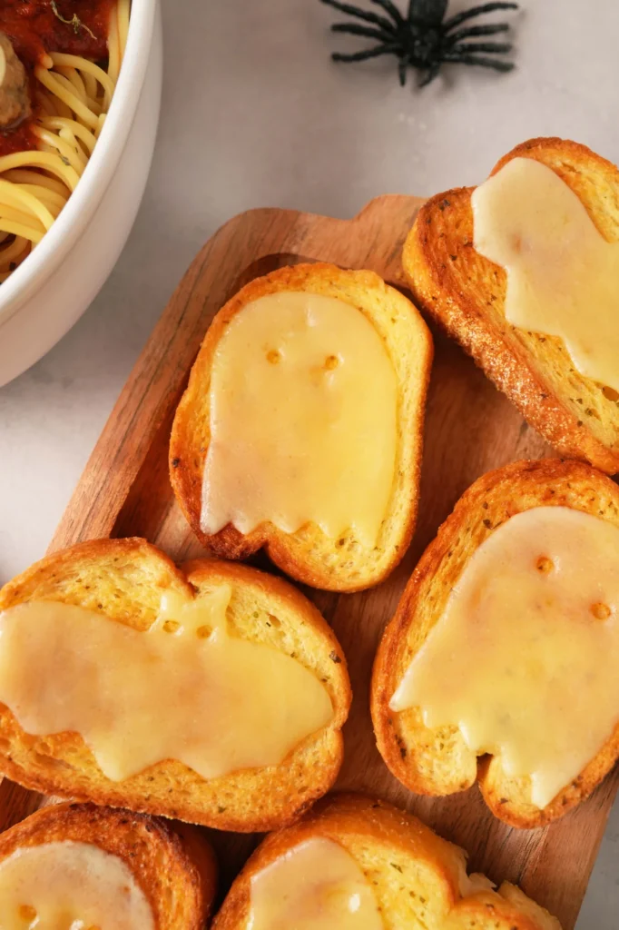 Garlic toast topped with ghost and bat-shaped cheese for a Halloween meal.