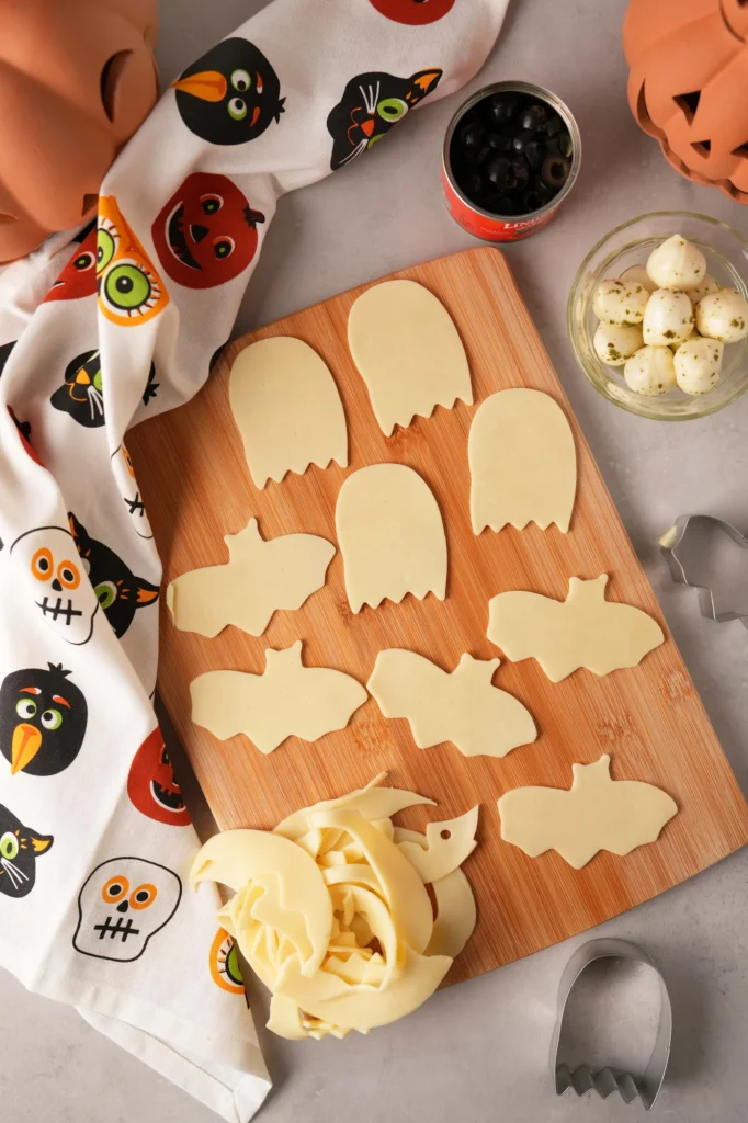 Ghost and bat-shaped cheese cutouts prepared for Halloween toast.