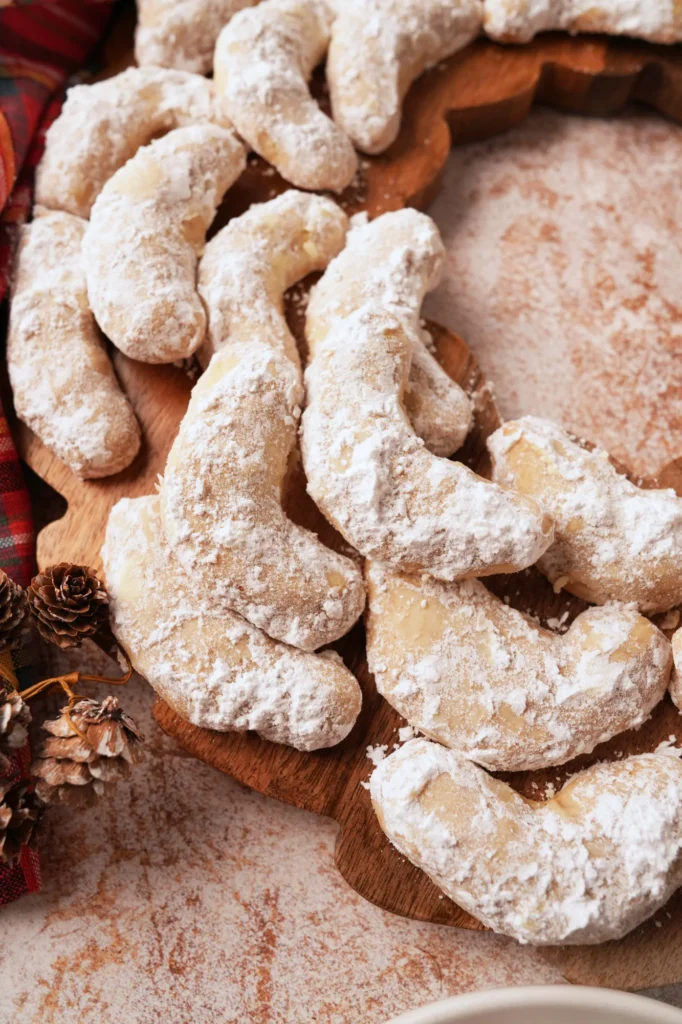 Finished Swedish heirloom cookies coated in powdered sugar on a wooden board.